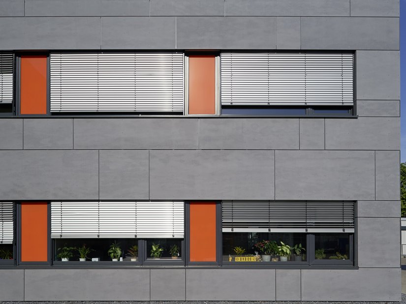 Die hinterlüftete Fassade aus Faserzementplatten ist in lichtem Grau gestaltet.