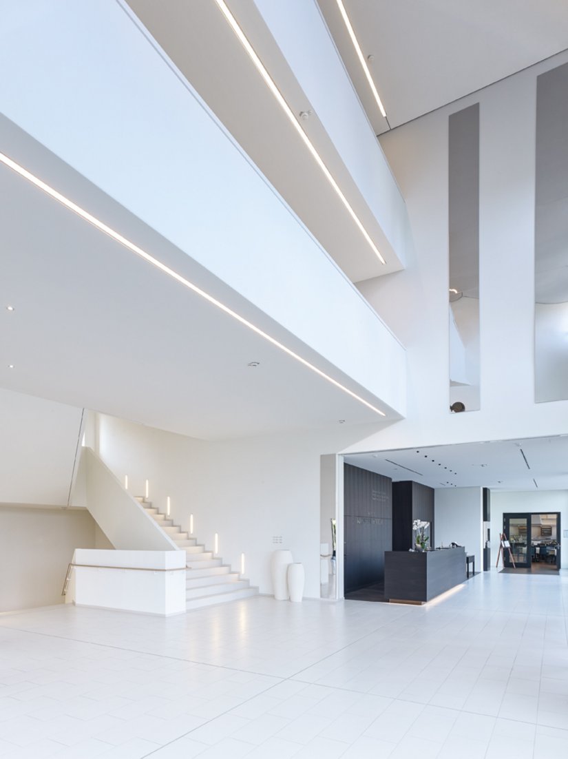Der haushohe Eingangsbereich erstrahlt in reinem Weiß und fügt sich dem Gestaltungskonzept des gesamten Gebäudes.