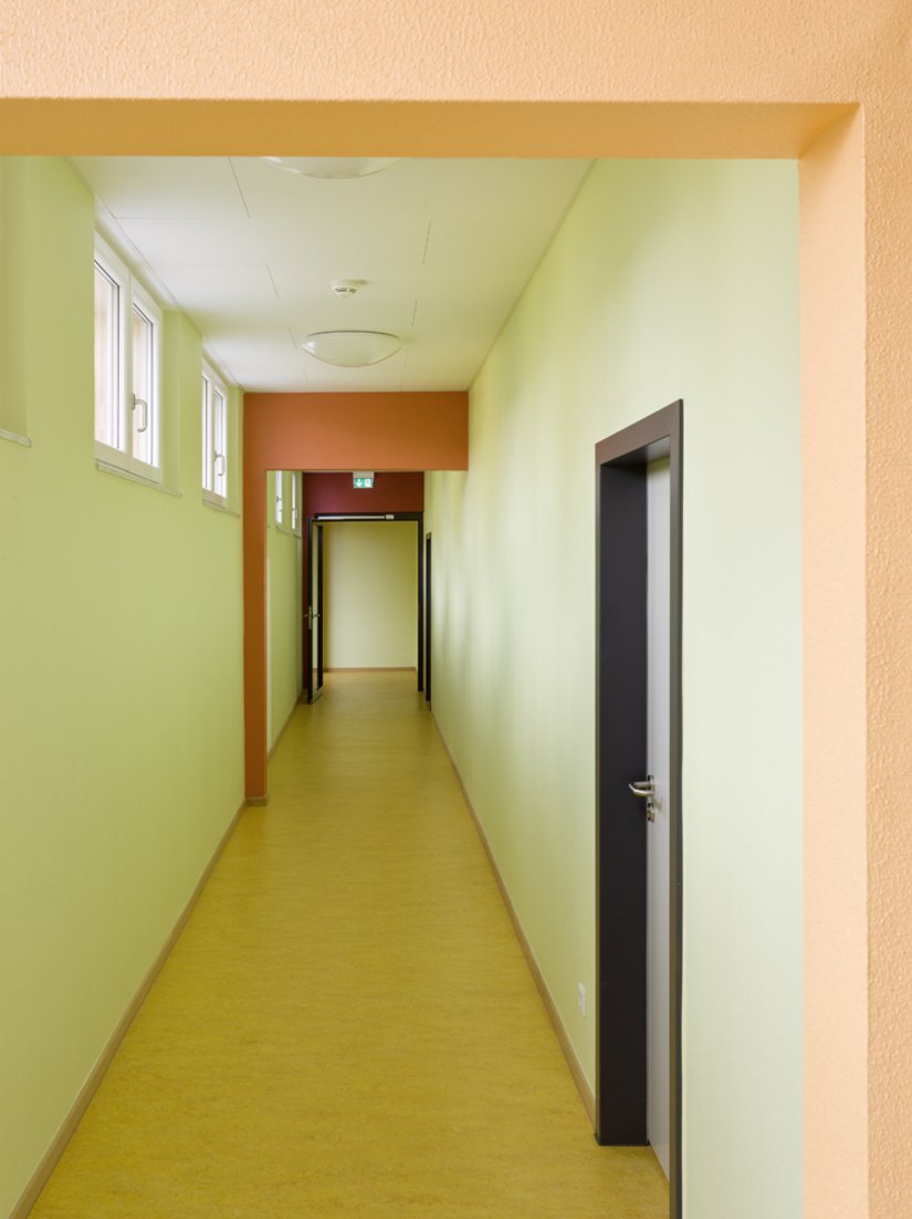 Durch den Farbverlauf wird der laubengangähnliche Durchgang zu den Klassenräumen bzw. zu der Verwaltung zu einem kurzweiligen Farberlebnis.