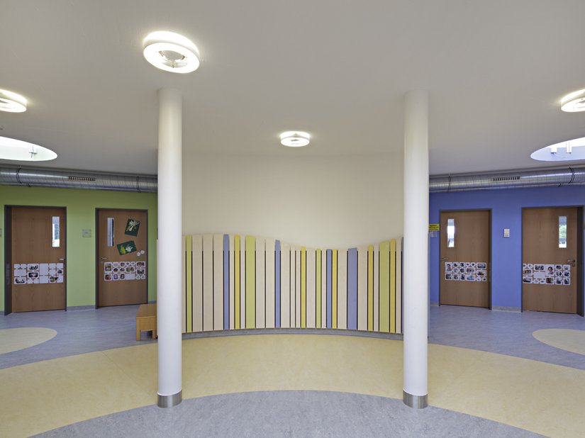 Intensive Farbtöne an den Wänden dienen zur Orientierung für die einzelnen Gruppen, pastellige Farbtöne sind auf den Holzlamellen zu finden.
