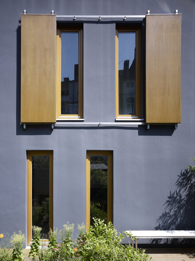 Die verschiebbaren Fensterläden lockern die sonst so gradlinige Fassade auf.