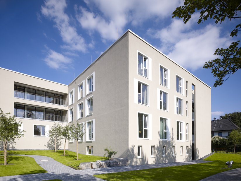 Ein sandgrauer Beigeton an der Fassade stellt eine Verbindung zum Boden und zur Natur her.