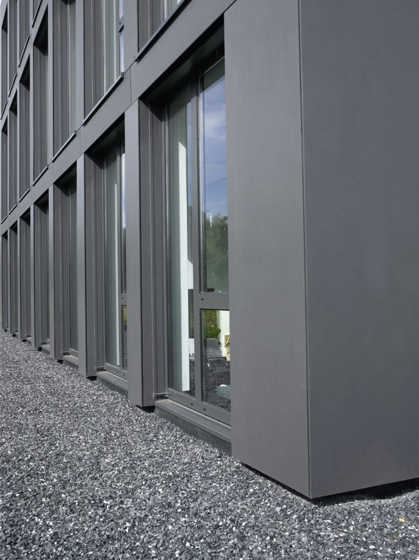 Die natürlich grauen Kieselsteine vor dem Bürogebäude runden das einheitliche Erscheinungsbild im Übergang zur Außenwelt ab.