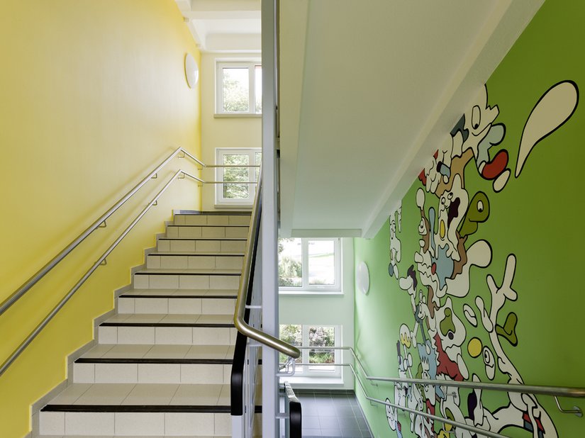 Das Treppenhaus der Grundschule. Der Gestaltungsschwerpunkt liegt hier nicht auf den durchgehenden Stützen, sondern auf der sehr kindgerechten und die Phantasie anregenden Gestaltung von Siebenstein.