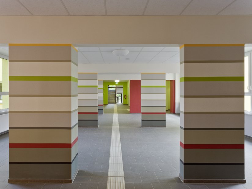 Die einst störenden Wandscheiben wurden das Besondere der Schule. Sie wurden in zur Decke gehörende Unterzüge und Stützen/Pfeiler unterteilt. Letztere wurden durch horizontale Streifen gestaltet, die bewusst durch farbige Bänder getrennt wurden.