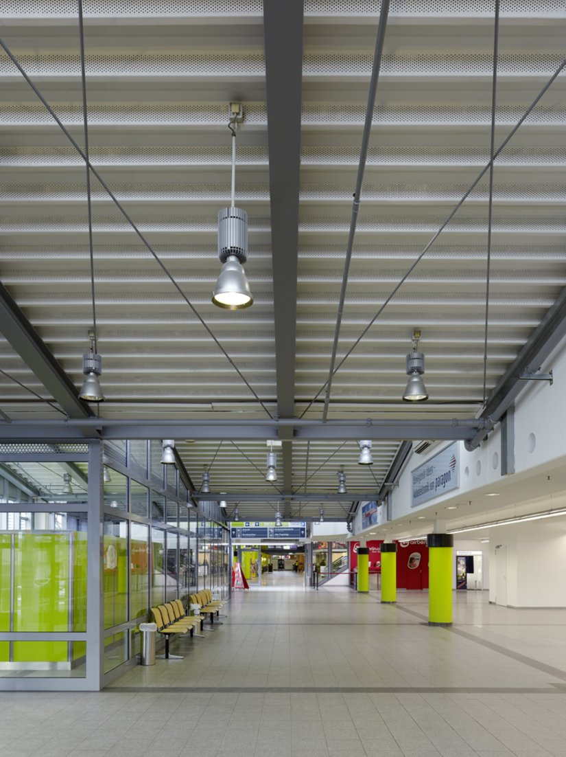 Der helle Deckenanstrich kombiniert mit dem hellen Boden und den leuchten grünen Akzenten auf Augenhöhe lassen die Halle des Paderborn Lippstadt Airports höher wirken.