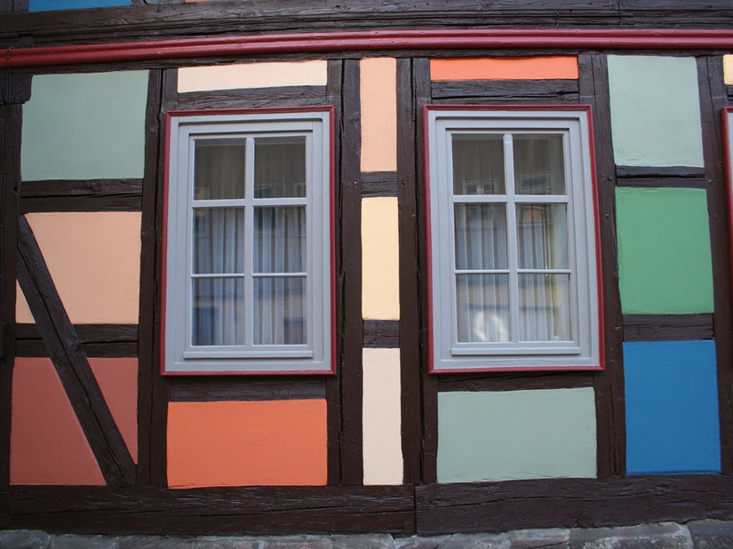 Das Holz wurde in einem dunklen Braun (Scala 15.06.30) beschichtet, die Fenster wurden in der Farbigkeit zurückgenommen und erhielten ein leicht farbiges Grau (Scala 18.06.18). Die Fenstereinfassungen erinnern dezent daran, dass diese in der gesamten Stadt farbig abgesetzt wurden.