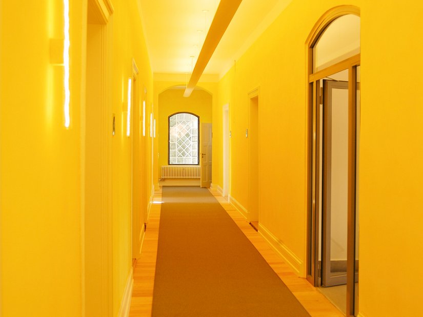 Gelb versinnbildlicht als ausstrahlende Farbe die Kommunikation. Die intensiv gelbe Lasur der Flure nimmt diese Gestaltungsidee auf.