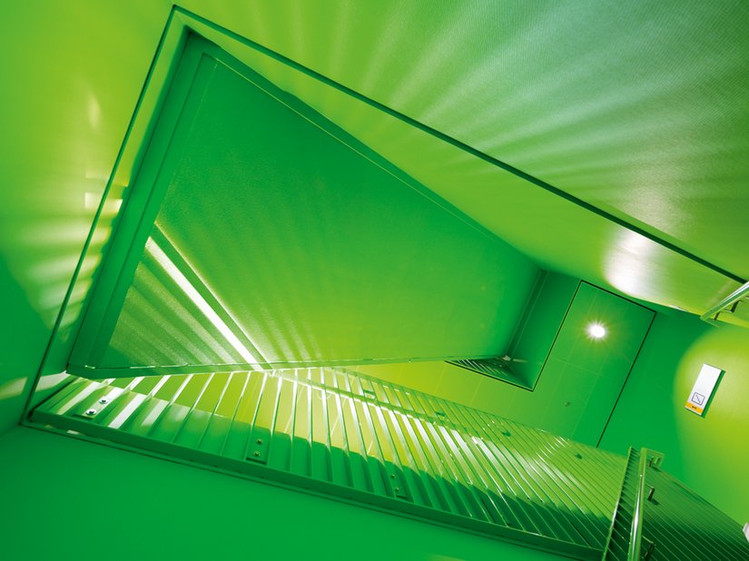 Ein komplett in Grün getauchtes Treppenhaus.