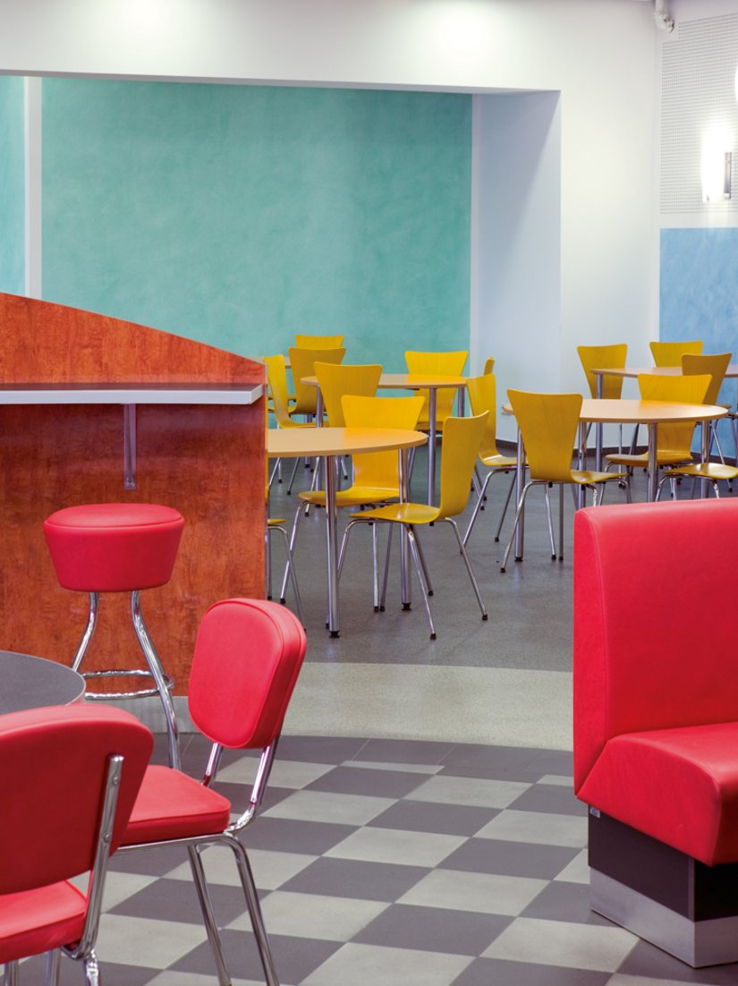 Noch einmal Betriebsrestaurant Halle 1 Nord: Sie ist in unterschiedliche Farb- und Erlebnisbereiche zoniert. Diese Gliederung spiegelt sich in Bestuhlung, Innenarchitektur und auch der Fußbodengestaltung wider.