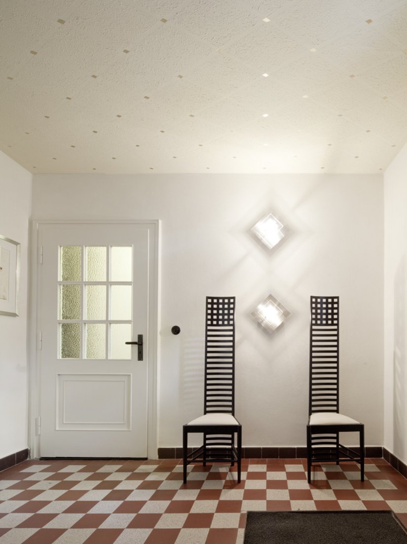 Formensprache aufnehmen und weiterentwickeln: Im Eingangsraum des Gebäudes spielen die Deckenornamente, die Bodenfliesen, das Mobiliar und die Lampen auf typische 1950er-Jahre-Ornamente an: das Quadrat und die Raute.
